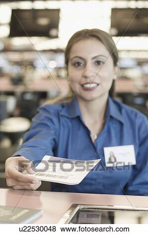 Stock Photo - Portrait of an airline check-in attendant holding a receipt at a counter. Fotosearch
