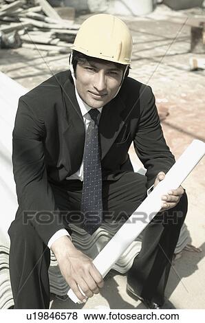 Portrait of an architect holding a blueprint at a construction site View Large Photo Image Stock Photo - Portrait of an architect holding a blueprint at a construction site. Fotosearch