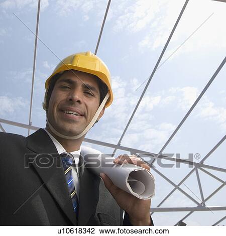 Portrait of an architect holding blueprints at a construction site View Large Photo Image Stock Image - Portrait of an architect holding blueprints at a construction site. Fotosearch