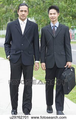 Stock Image - Portrait of two businessmen walking together. Fotosearch