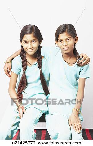 Portrait of two girls sitting on a stool with their arms around each other View Large Photo Image Stock Photo - Portrait of two girls sitting on a stool with their arms around each other. Fotosearch