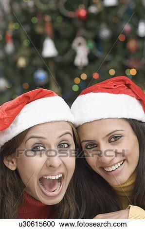 Portrait of two young women wearing Santa hats View Large Photo Image Stock Image - Portrait of two young women wearing Santa hats. Fotosearch