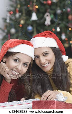 Stock Photo - Portrait of two young women wearing Santa hats. Fotosearch