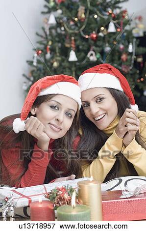 Stock Photo - Portrait of two young women wearing Santa hats. Fotosearch