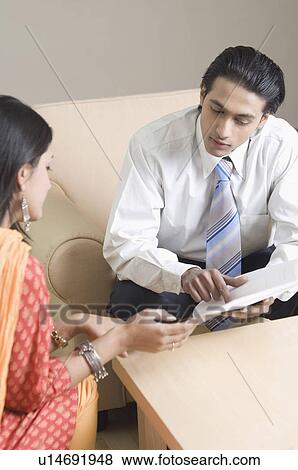 Stock Photo - Real estate agent discussing a document with a young woman. Fotosearch