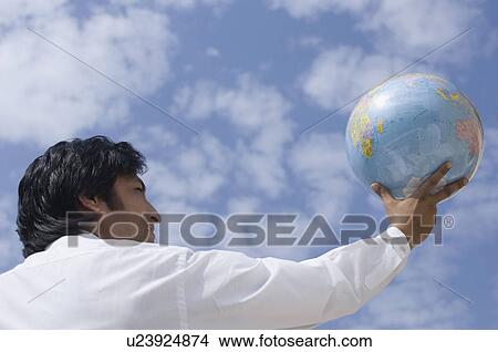Rear view of a businessman holding a globe View Large Photo Image Picture - Rear view of a businessman holding a globe. Fotosearch