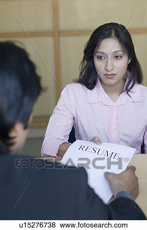 Rear view of a businessman taking resume from a young woman View Large Photo Image Stock Photo - Rear view of a businessman taking resume from a young woman. Fotosearch