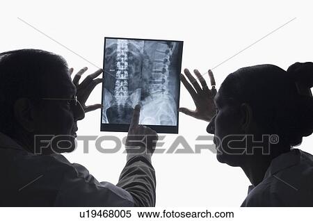 Stock Photography - Rear view of a male doctor with a female doctor examining an X-Ray . Fotosearch