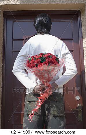 Rear view of a man hiding a bouquet of flowers behind his back View Large Photo Image Stock Photo - Rear view of a man hiding a bouquet of flowers behind his back. Fotosearch