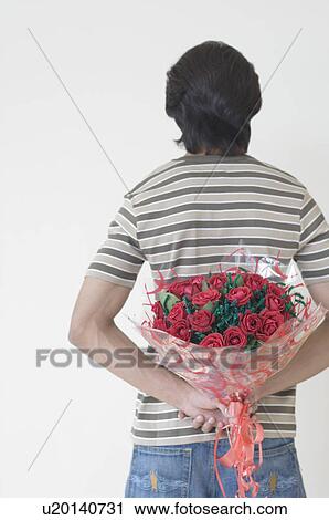 Rear view of a man holding a bouquet of flowers behind his back View Large Photo Image Stock Image - Rear view of a man holding a bouquet of flowers behind his back. Fotosearch