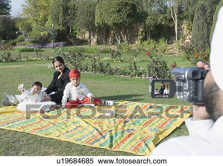 Rear view of a mid adult man making a video of his family with a video camera View Large Photo Image Stock Photography - Rear view of a mid adult man making a video of his family with a video camera. Fotosearch