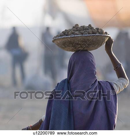 Stock Photo - Rear view of a woman carrying a tub of stones. Fotosearch