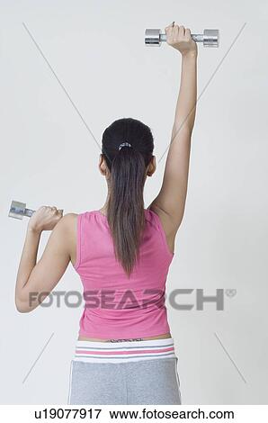 Stock Photo - Rear view of a woman exercising with dumbbells. Fotosearch