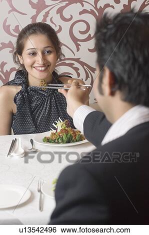 Rear view of a young man feeding a young woman in a restaurant View Large Photo Image Stock Photograph - Rear view of a young man feeding a young woman in a restaurant. Fotosearch