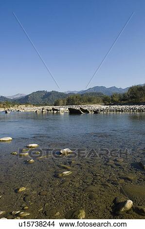 Picture - River flowing on rocks with mountains in the background, Jim Corbett National Park, Pauri Garhwal, Uttarakhand, India. Fotosearch