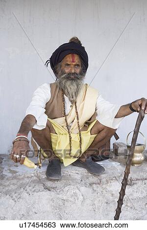 Sadhu holding a cane and crouching on a parapet wall View Large Photo Image Stock Image - Sadhu holding a cane and crouching on a parapet wall. Fotosearch