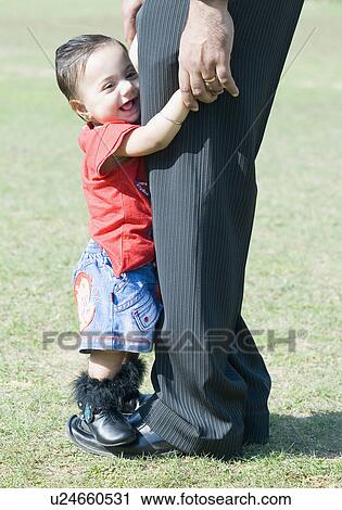 Stock Image - Side profile of a baby girl standing on her father's feet. Fotosearch