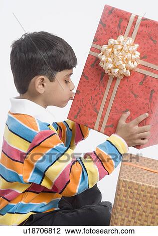 Stock Image - Side profile of a boy holding and kissing a gift. Fotosearch