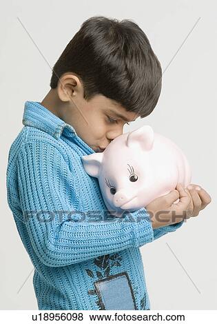 Side profile of a boy kissing a piggy bank View Large Photo Image Stock Photo - Side profile of a boy kissing a piggy bank. Fotosearch