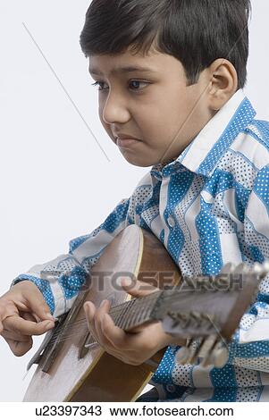 Stock Image - Side profile of a boy playing the mandolin. Fotosearch