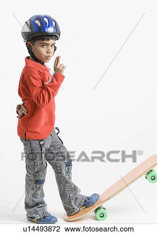 Stock Image - Side profile of a boy standing on a skateboard. Fotosearch
