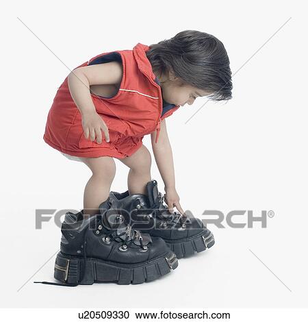 Stock Image - Side profile of a boy wearing oversized hiking boots. Fotosearch
