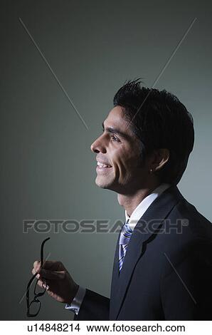 Picture - Side profile of a businessman holding eyeglasses. Fotosearch