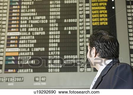 Side profile of a businessman looking at a flight schedule board View Large Photo Image Stock Image - Side profile of a businessman looking at a flight schedule board. Fotosearch