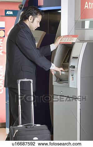 Side profile of a businessman using an ATM machine View Large Photo Image Stock Image - Side profile of a businessman using an ATM machine. Fotosearch