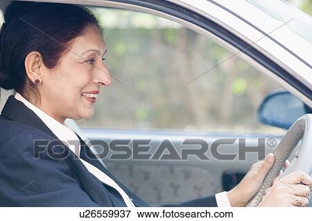 Stock Photo - Side profile of a businesswoman driving a car. Fotosearch