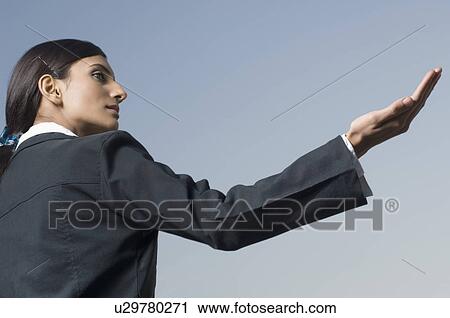 Stock Image - Side profile of a businesswoman holding her palm out. Fotosearch