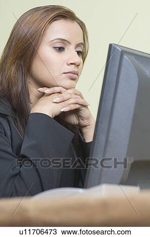Side profile of a businesswoman sitting in front of a computer with her hand under her chin View Large Photo Image Stock Image - Side profile of a businesswoman sitting in front of a computer with her hand under her chin. Fotosearch