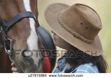 Picture - Side profile of a teenage girl touching a horse. Fotosearch