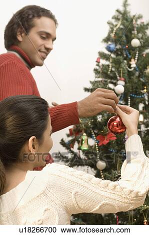 Side profile of a young couple decorating a Christmas tree View Large Photo Image Stock Image - Side profile of a young couple decorating a Christmas tree. Fotosearch