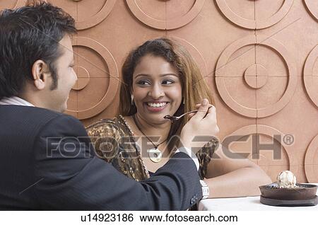 Side profile of a young man feeding dessert to a young woman View Large Photo Image Stock Photograph - Side profile of a young man feeding dessert to a young woman. Fotosearch