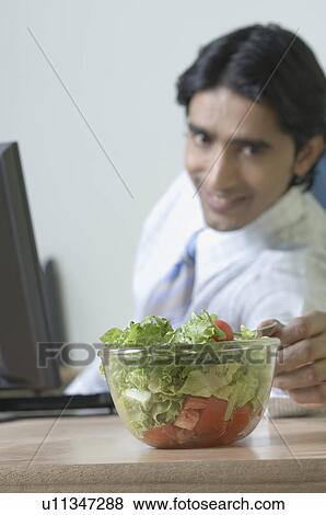 Side profile of a young man reaching to a bowl of salad View Large Photo Image Stock Photo - Side profile of a young man reaching to a bowl of salad. Fotosearch