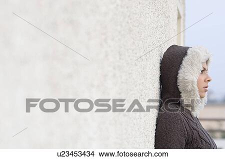 Picture - Side profile of a young woman leaning against a wall. Fotosearch