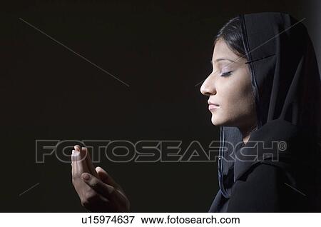 Stock Photo - Side profile of a young woman praying. Fotosearch
