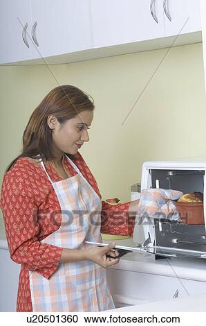 Side profile of a young woman putting a cake in the oven View Large Photo Image Stock Image - Side profile of a young woman putting a cake in the oven. Fotosearch