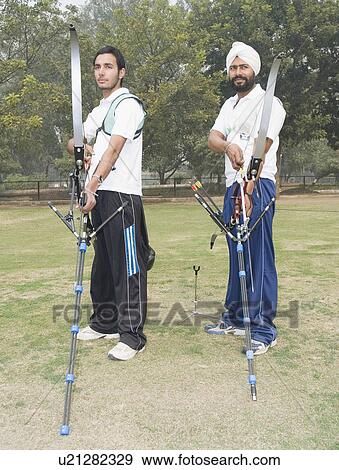 Stock Photo - Side profile of two young men holding bows and arrows. Fotosearch