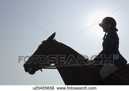 Stock Photo - Silhouette of a female jockey riding a horse. Fotosearch