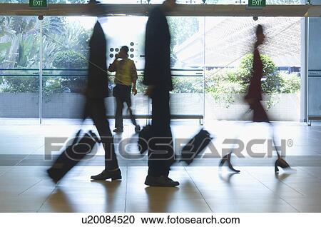 Stock Image - Silhouette of four people walking with their luggage. Fotosearch
