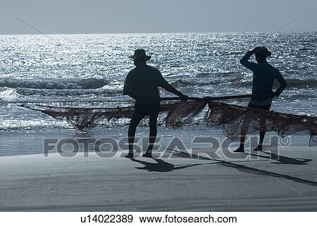 Silhouette of two men holding a fishing net on the beach, Morjim Beach, Goa, India View Large Photo Image Stock Photo - Silhouette of two men holding a fishing net on the beach, Morjim Beach, Goa, India. Fotosearch