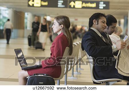 Stock Image - Three business executives sitting at an airport lounge. Fotosearch