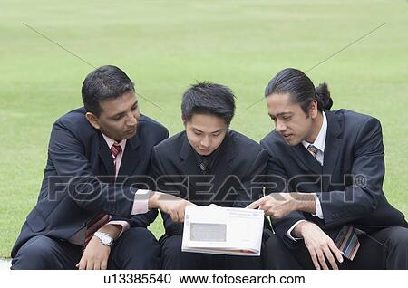 Three businessmen looking at a magazine View Large Photo Image Stock Image - Three businessmen looking at a magazine. Fotosearch