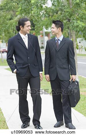 Two businessmen looking at each other and smiling View Large Photo Image Stock Image - Two businessmen looking at each other and smiling. Fotosearch