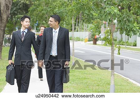 Stock Image - Two businessmen looking at each other and walking. Fotosearch
