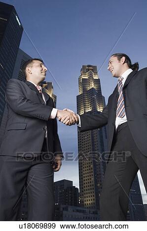 Stock Photo - Two businessmen shaking hands and smiling. Fotosearch
