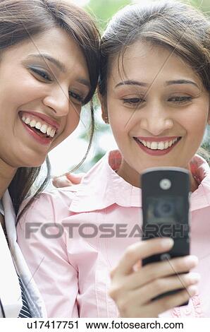 Stock Image - Two businesswomen looking at a mobile phone. Fotosearch