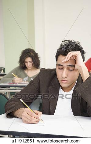 Stock Image - Two college students giving an exam in a classroom. Fotosearch
